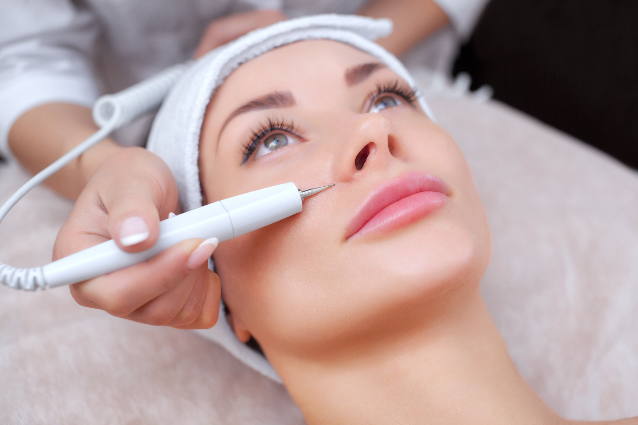 The doctor-cosmetologist makes the procedure treatment of Couperose of the facial skin of a beautiful, young woman in a beauty salon.Cosmetology and professional skin care.